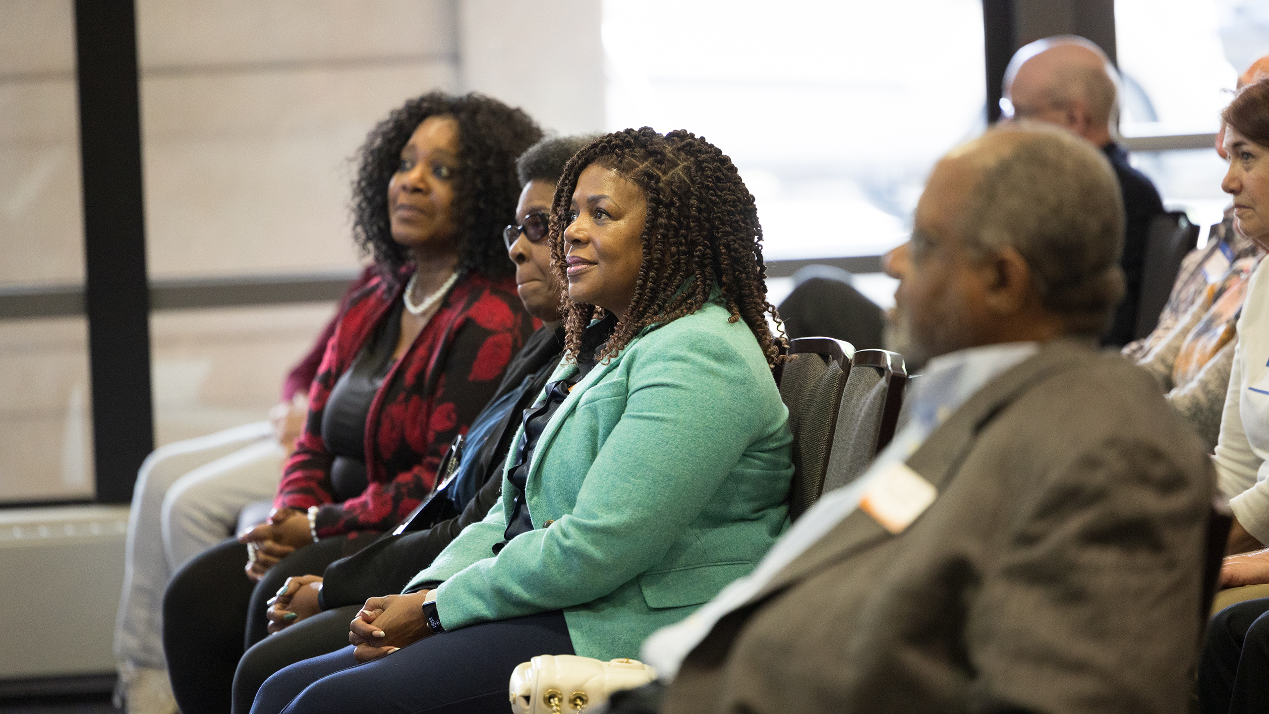 Three Black women watch the speaker at the Stevens & Smith Groundbreaking Ceremony.