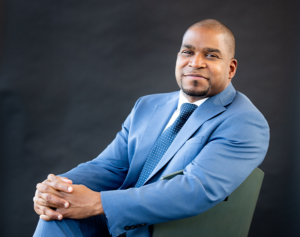 An image of Melvin Rogers, a Black man wearing a bright blue suit. 